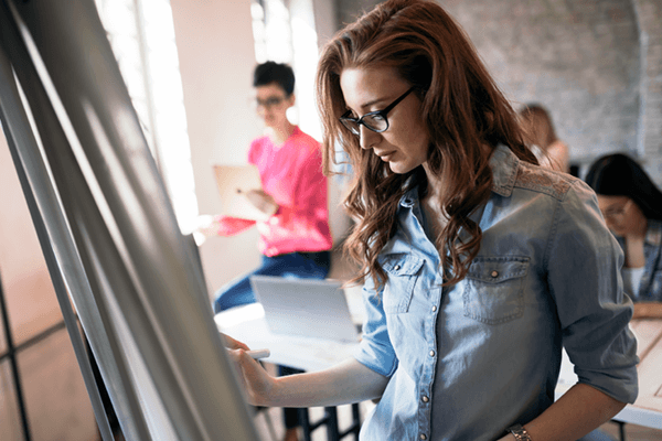 Business woman drawing out ideas on easel in modern office