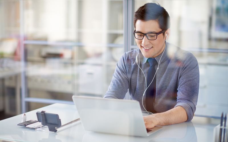 Businessman taking conference call on laptop device with earbuds