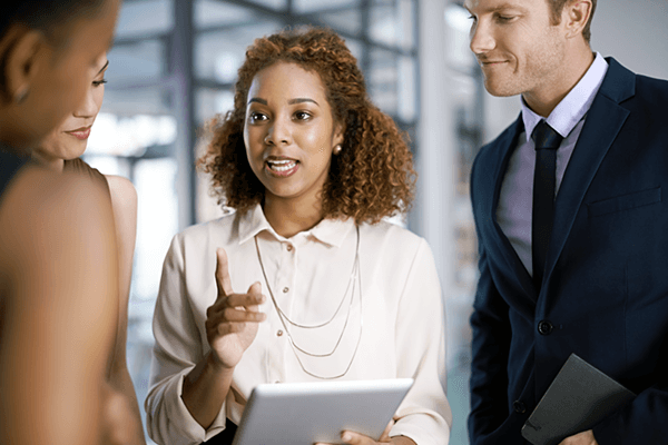 Business professionals gather around woman with tablet to hear workflow ideas