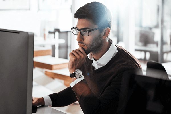 Serious businessman monitors usage of software on computer