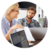 Business professionals discuss data over laptop computers
