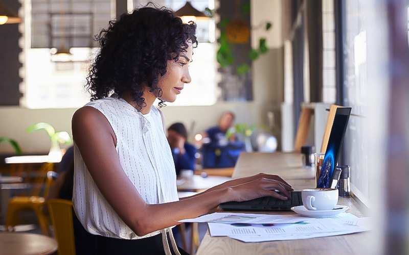 Conçu pour le travail hybride Femme utilisant son ordinateur portable Lenovo au café.
