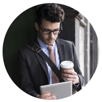 Business man on tablet holding cup of coffee.