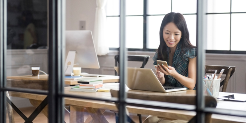 Business woman views information found on laptop and phone