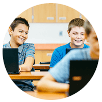 Three school children looking at 2 laptops.