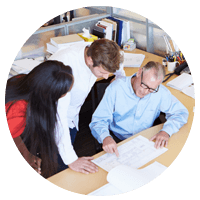 Three employees looking over paperwork at desk