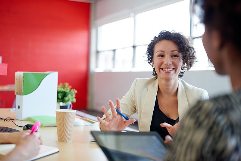 Break down silos and increase efficiencies. Business woman has discussion with employee on tablet computer.