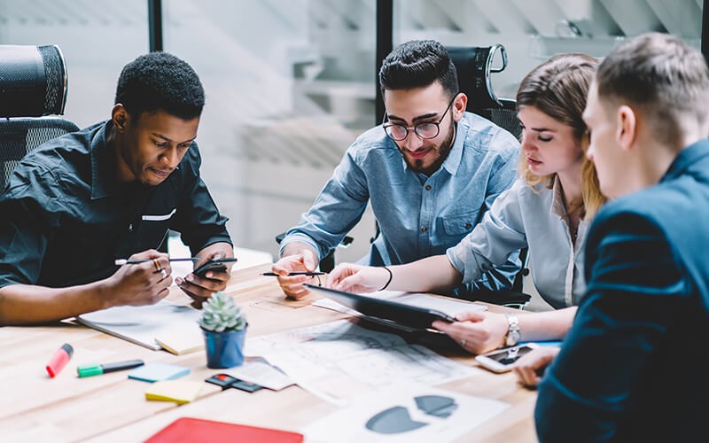 A critical component of any zero-trust strategy is securing the workplace that everyone and everything connects to Team of four working on their tablet and phone