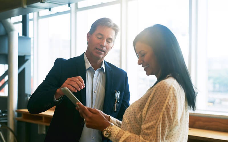 Two business professionals having discussion over tablet device