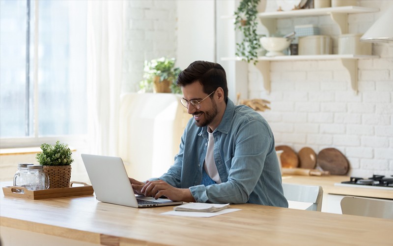 man working at laptop in kitchen