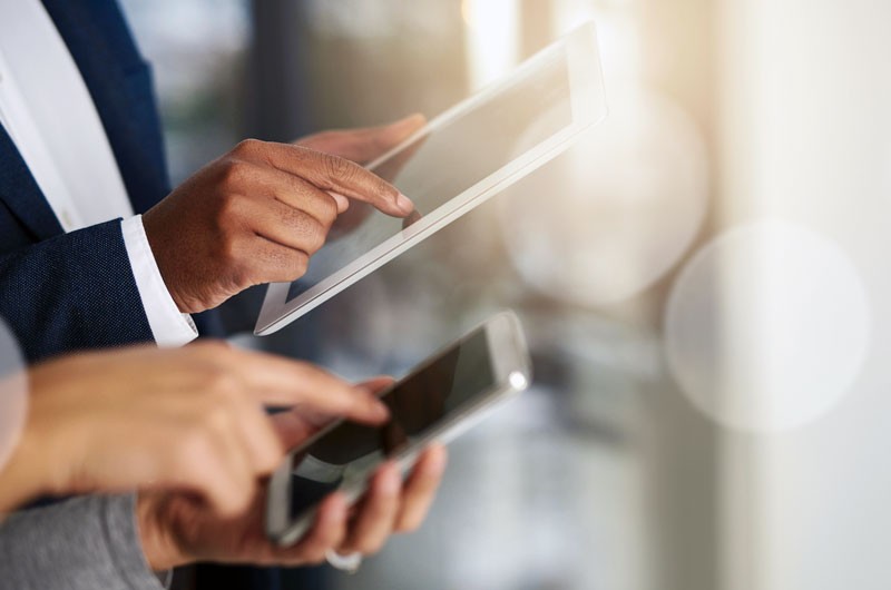 Achieve an IoT-powered business model Tablet computer and smart phone in business persons hands