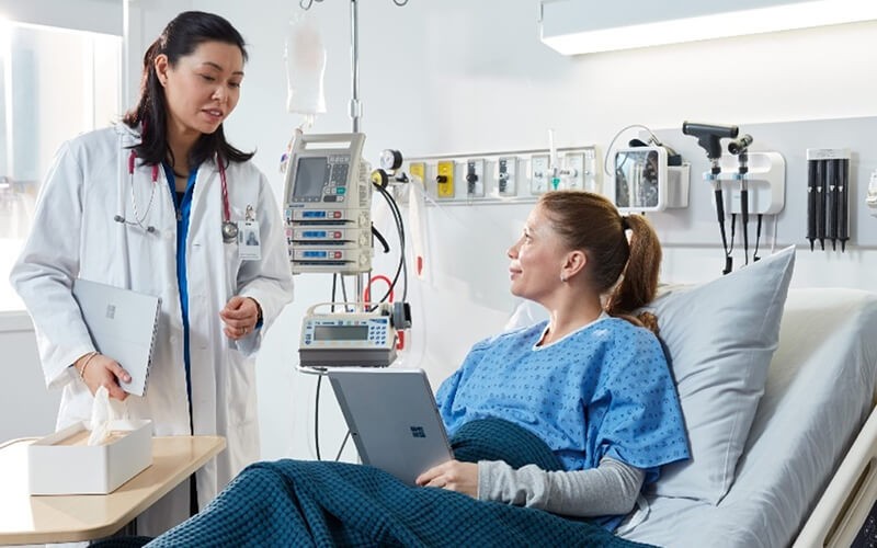 Unlock your full potential. Doctor talking to the patient holding the Microsoft Surface tablet