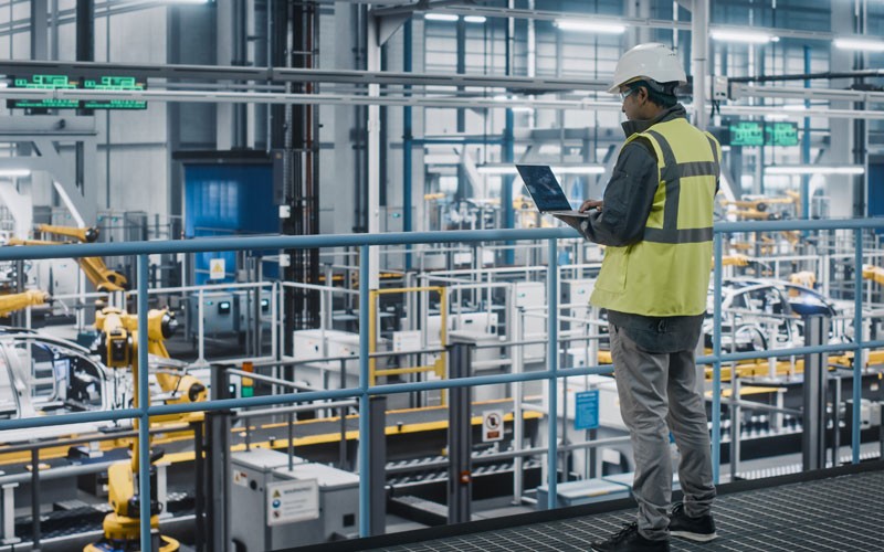 Streamline technology procurement and management Man in hard hat on laptop in warehouse