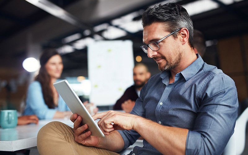 Manage your mobile workforce with ease. Two business colleagues use mobile tablet device