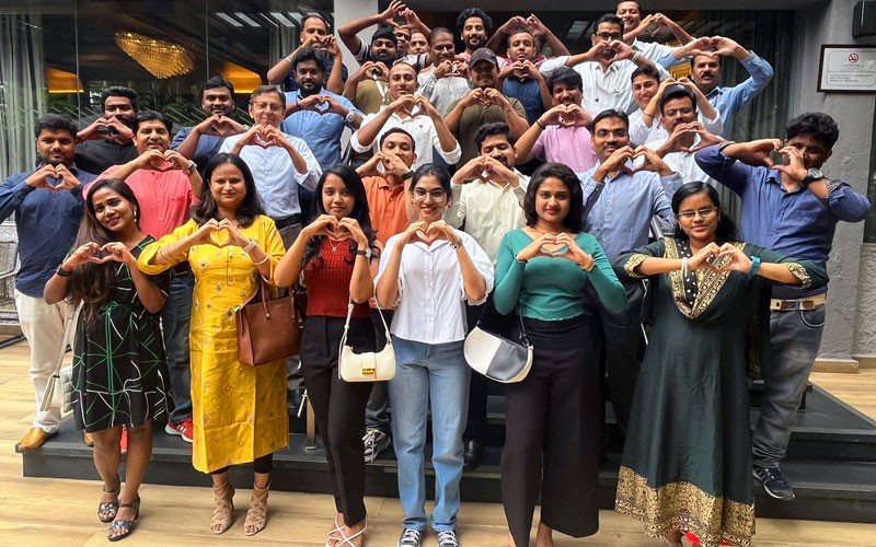 Our teammates contribute distinct life experiences, viewpoints and backgrounds Group of business professionals from Insight India holding up heart symbols with hands