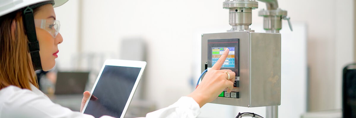 Manufacturing worker uses a tablet to control a machine.