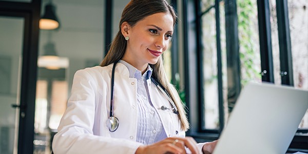 Nurse working on laptop computer. Reading report. 