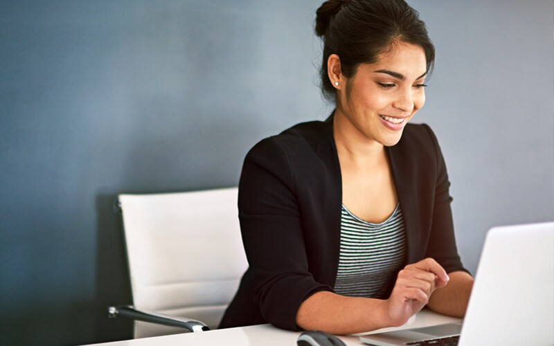 Woman reviewing information found in a report from her desktop computer