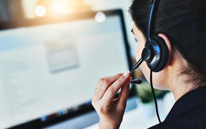 Woman on headset device using laptop computer