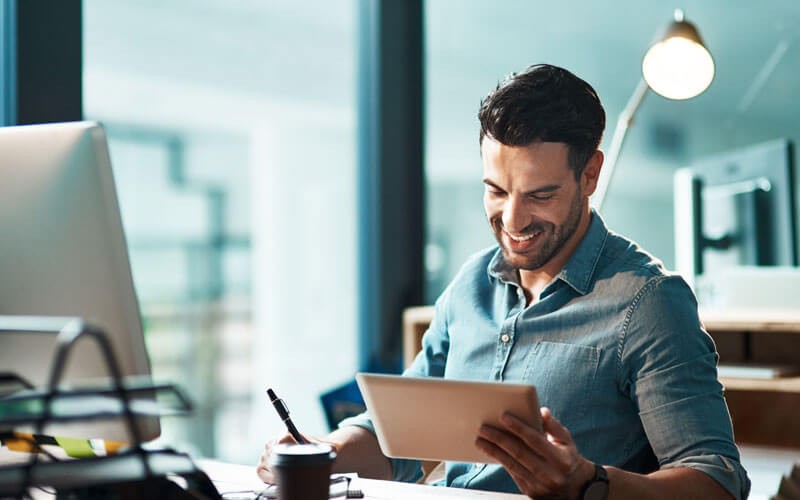 Smiling man reading report on tablet device