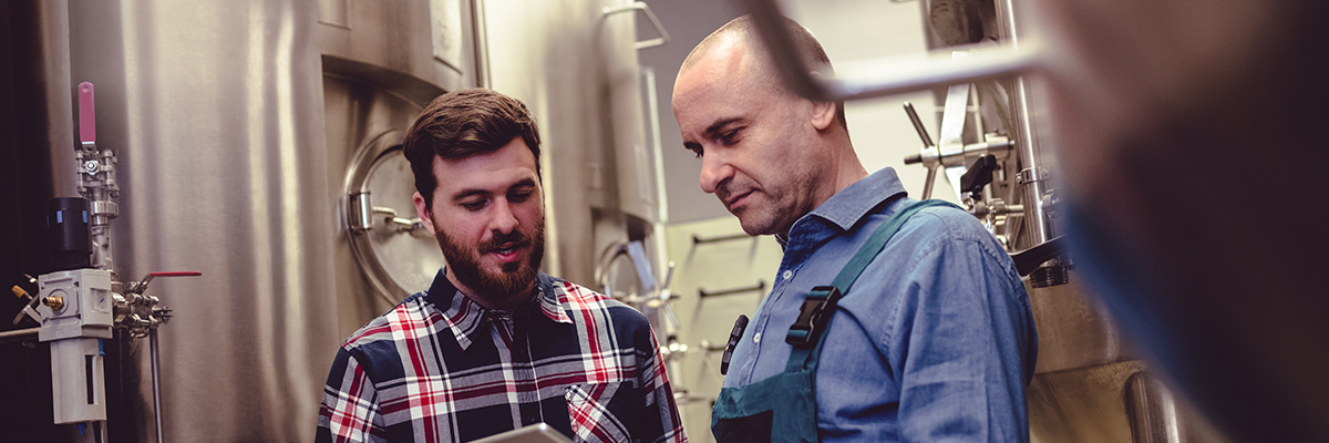 Two workers in fridge area of alcoholic beverage conglomerate