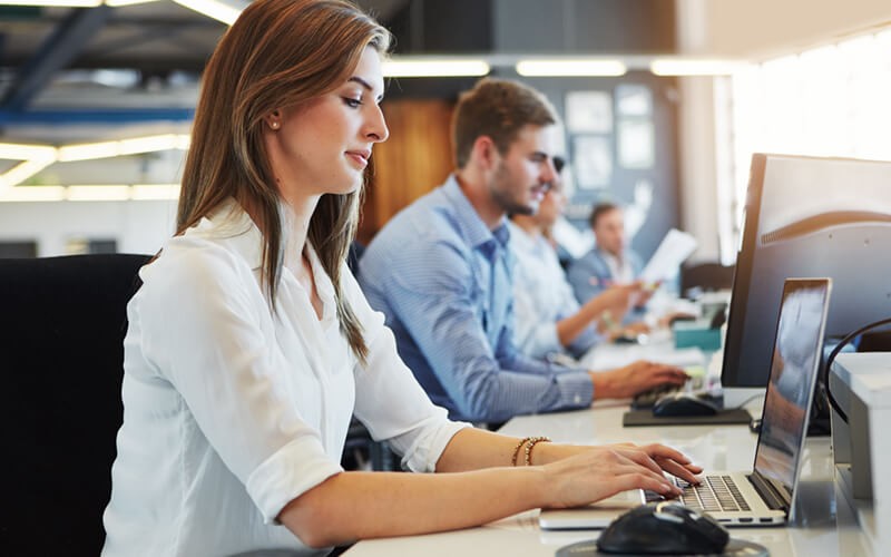 Businesswoman in open office using software on desktop computer