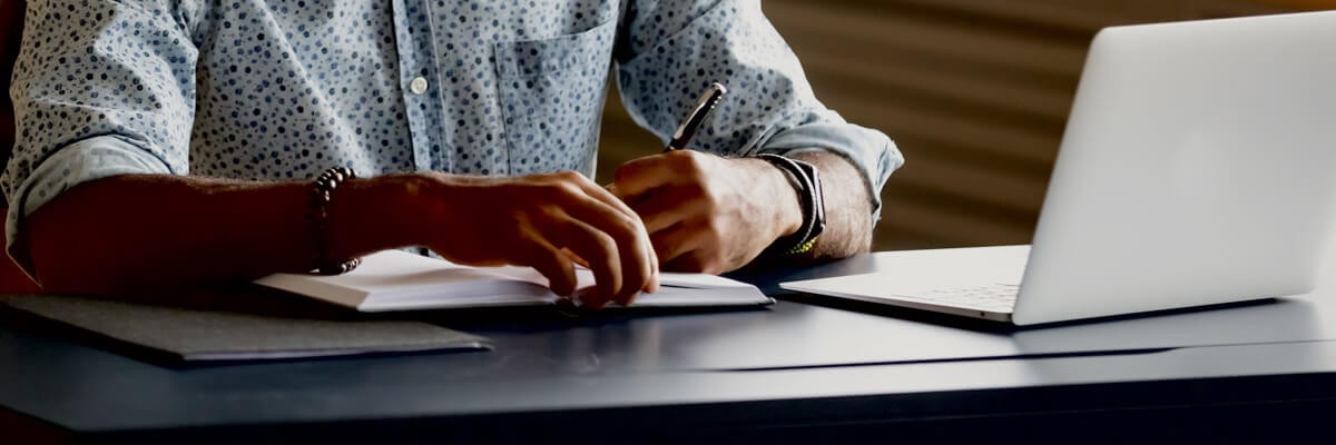 Person reading and using laptop at a desk