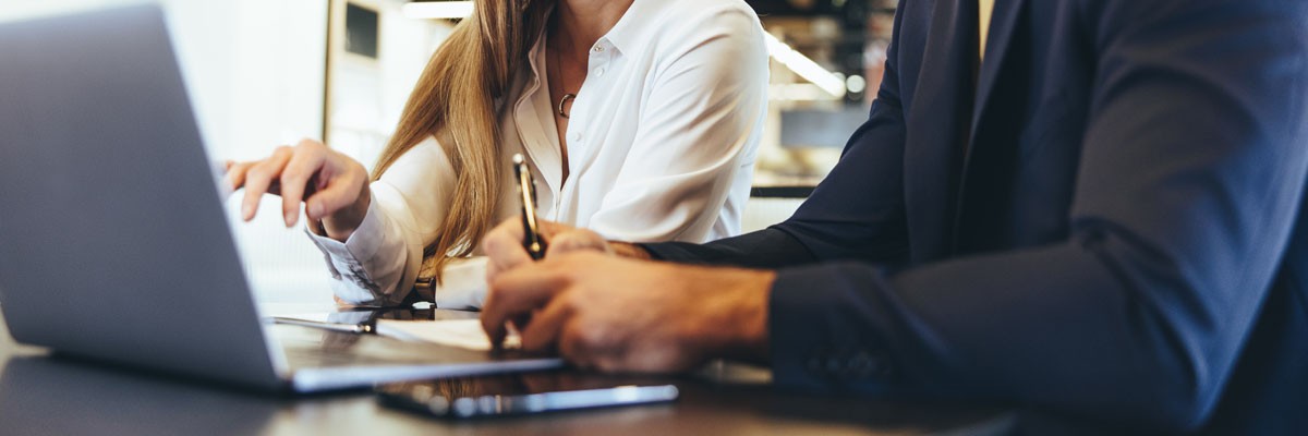 Businessman and woman collaborate on laptop device in office