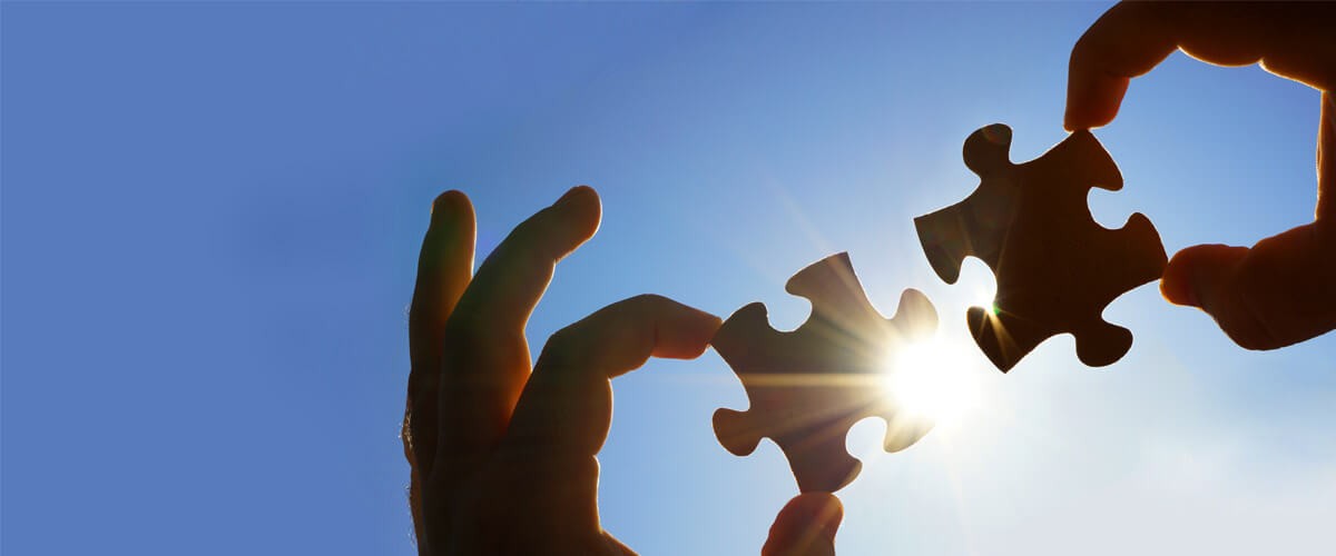 two puzzle pieces being held up to the sun