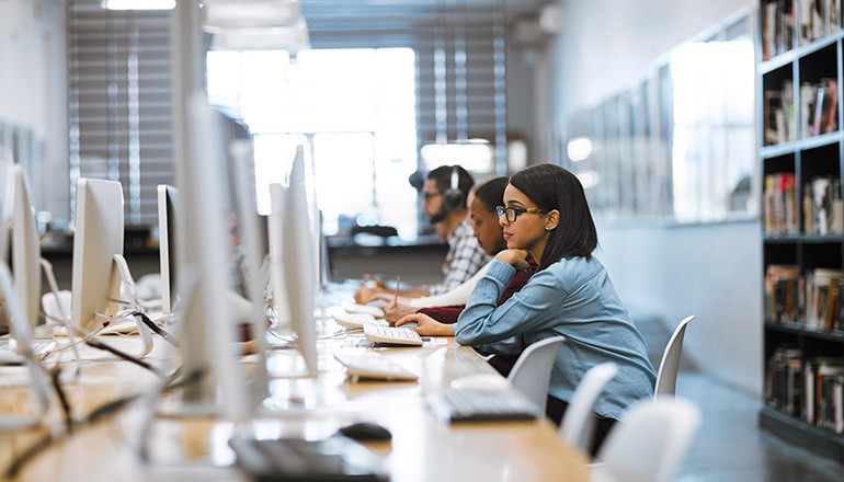 Higher Education student using computer in library