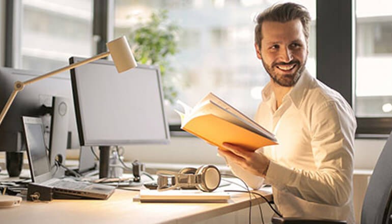 IT professional smiling while reviewing documents at computer. Check Point security solutions