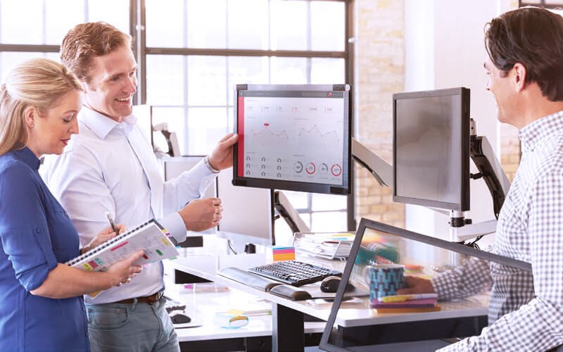 Configure your space. Teammates collaborating together using a 3M Monitor Arms