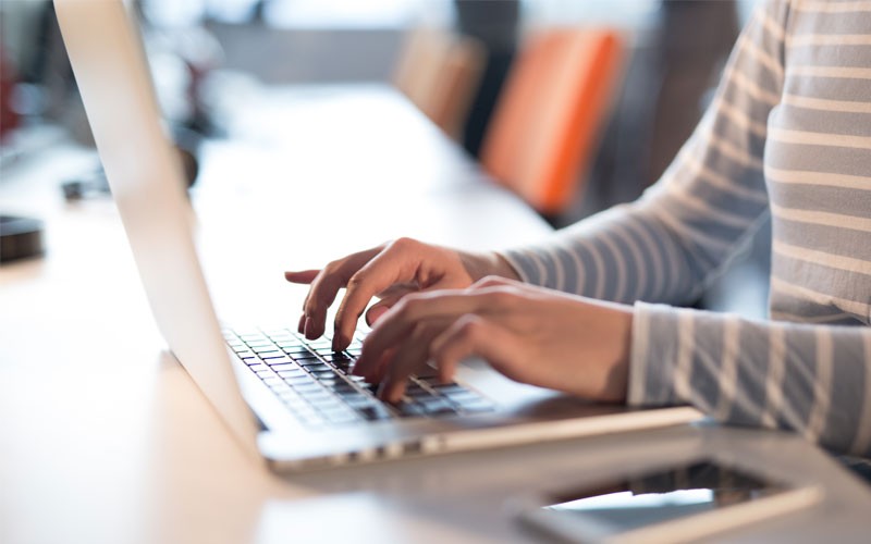 Close up of woman typing on laptop keyboard Detect and respond to DDoS attacks