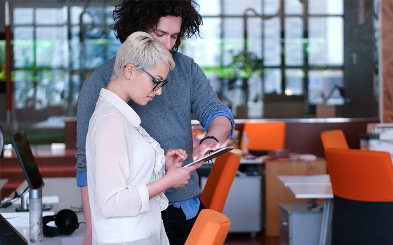 Woman and man collaborating on tablet device AWS offers tools to help your organization