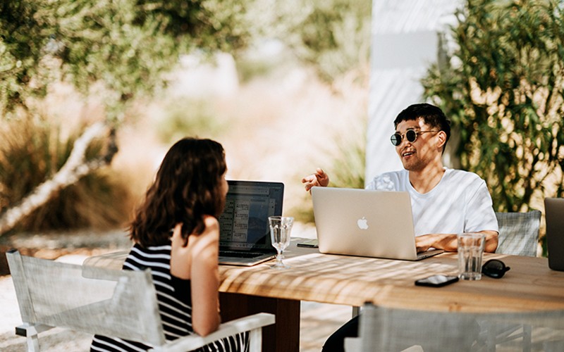 Increase Apple adoption with expert support. Two people working outside on laptops