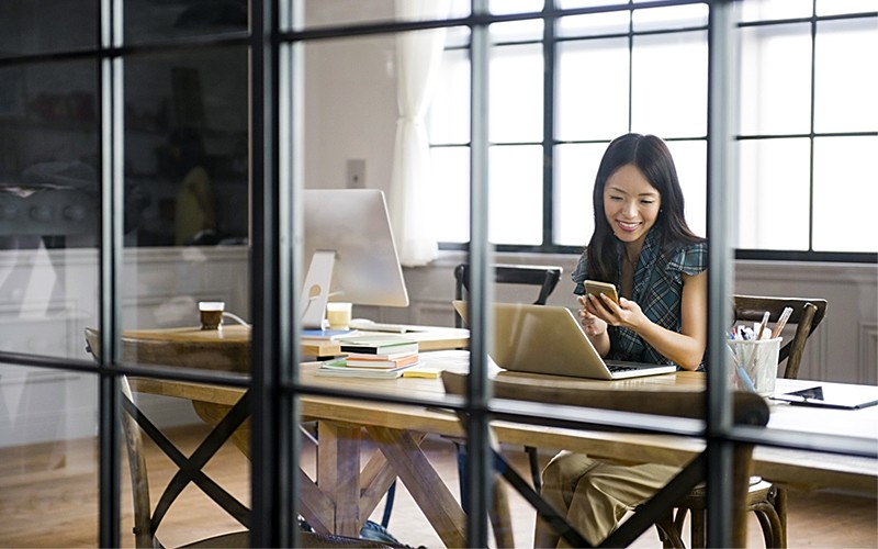 DataStax Enterprise data platform for cloud application Business woman in office smiling at mobile device and laptop