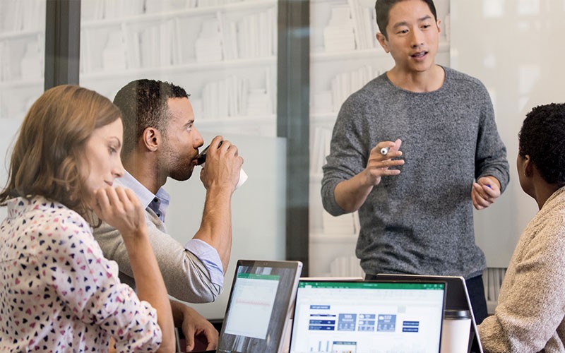Microsoft 365 for business to help teams achieve success Group of professionals working in meeting