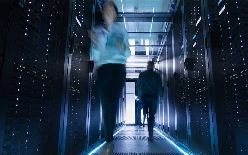 two-people-walking-through-server-room two-people-walking-through-server-room