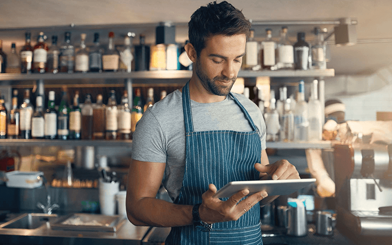 Man in apron using a tablet