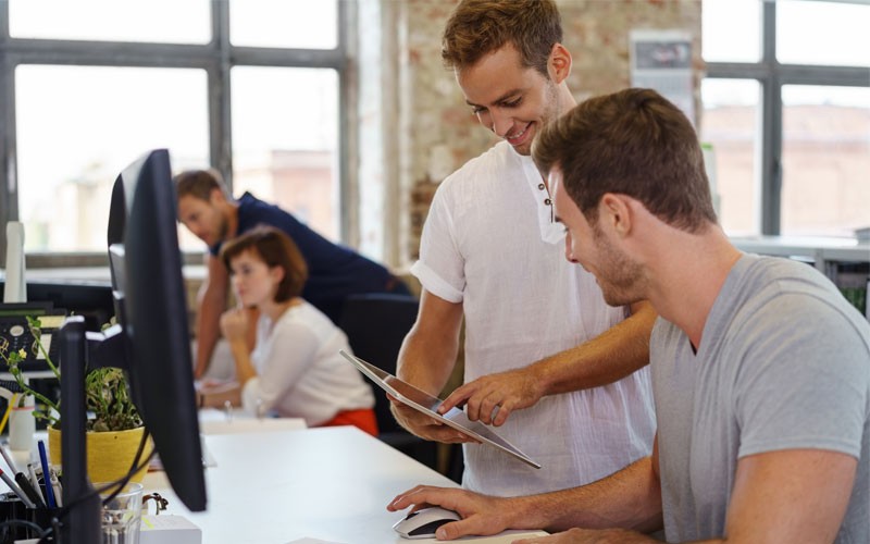 Proofpoint Information Protection solutions continuously monitor activity across emails and the cloud, Team collaborating at desks