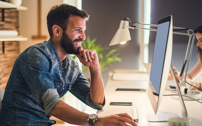 Foglight Database Performance Monitoring Man working on desktop smiling