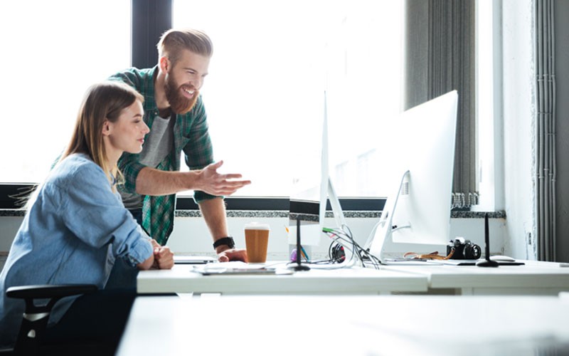 Easily customize your version of Enterprise Linux Two smiling business colleagues collaborate over desktop computer