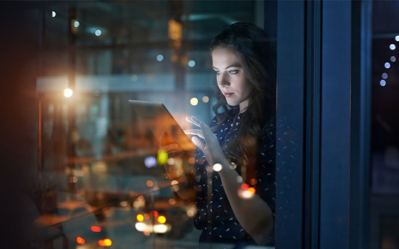 SonicWall Analyzer provides a way to deploy and manage your security solutions Woman using touch screen device in open office late at night