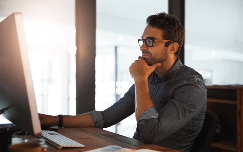 Symantec Cloud Access Security Broker Man smiling while working on monitor screen