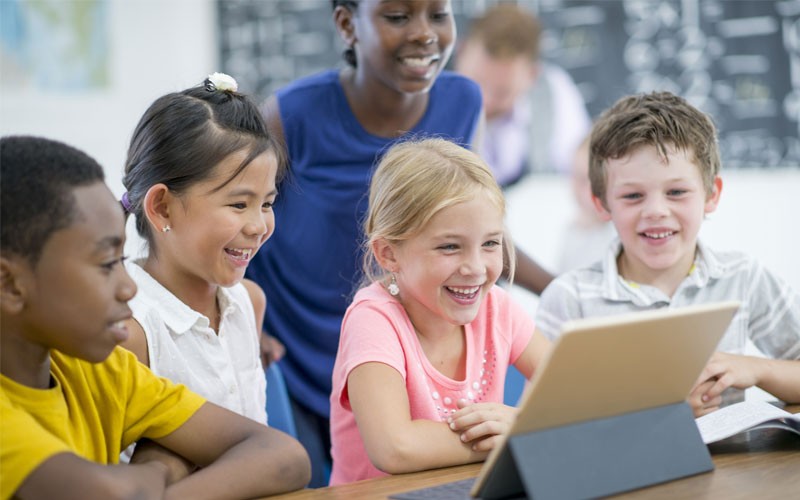 VMware is providing technology that helps educators teach Group of kids in a classroom looking at tablet