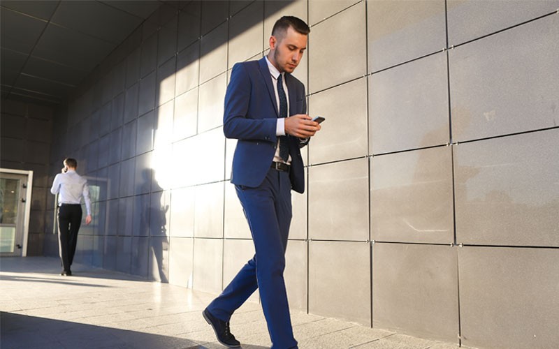 VMware digital workspace solutions empower employees with workforce mobility and reliable access to data Business man walking outside while texting on mobile phone