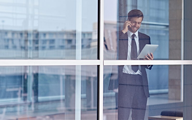 Transform your organization with IT today Business man on mobile phone while holding tablet device