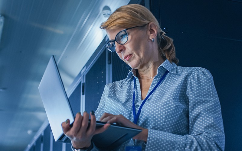 Modernization helps software teams optimize existing applications for these more distributed computing paradigms Woman using laptop on data center