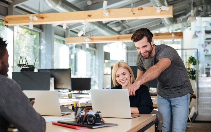 VMware vRealize Suite to form a multivendor hybrid cloud platform Two employees helping each other with laptop device