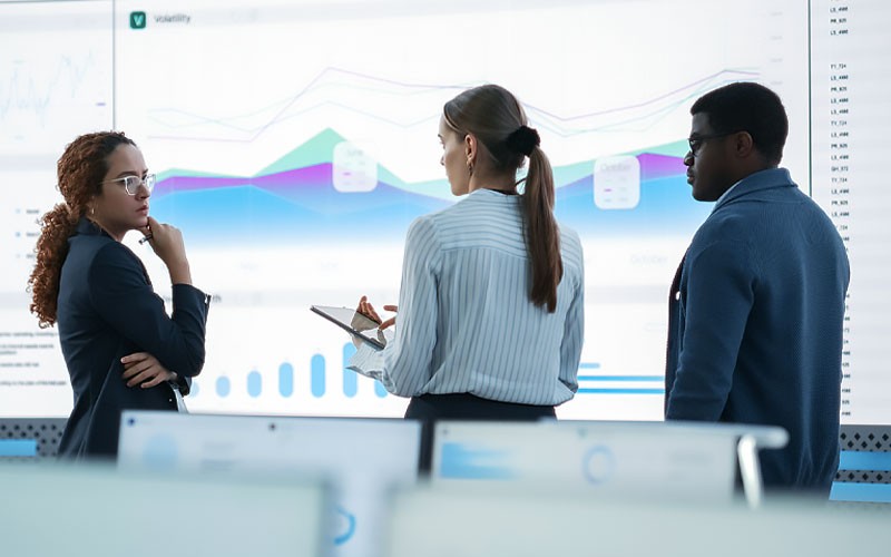 Take the next step in your analytics journey with Insight. Group of business professionals gathered around screen displaying data analytics